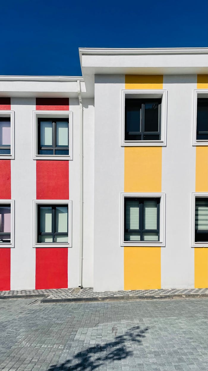 Modern building facade with red and yellow stripes creating a vibrant, minimalistic look.